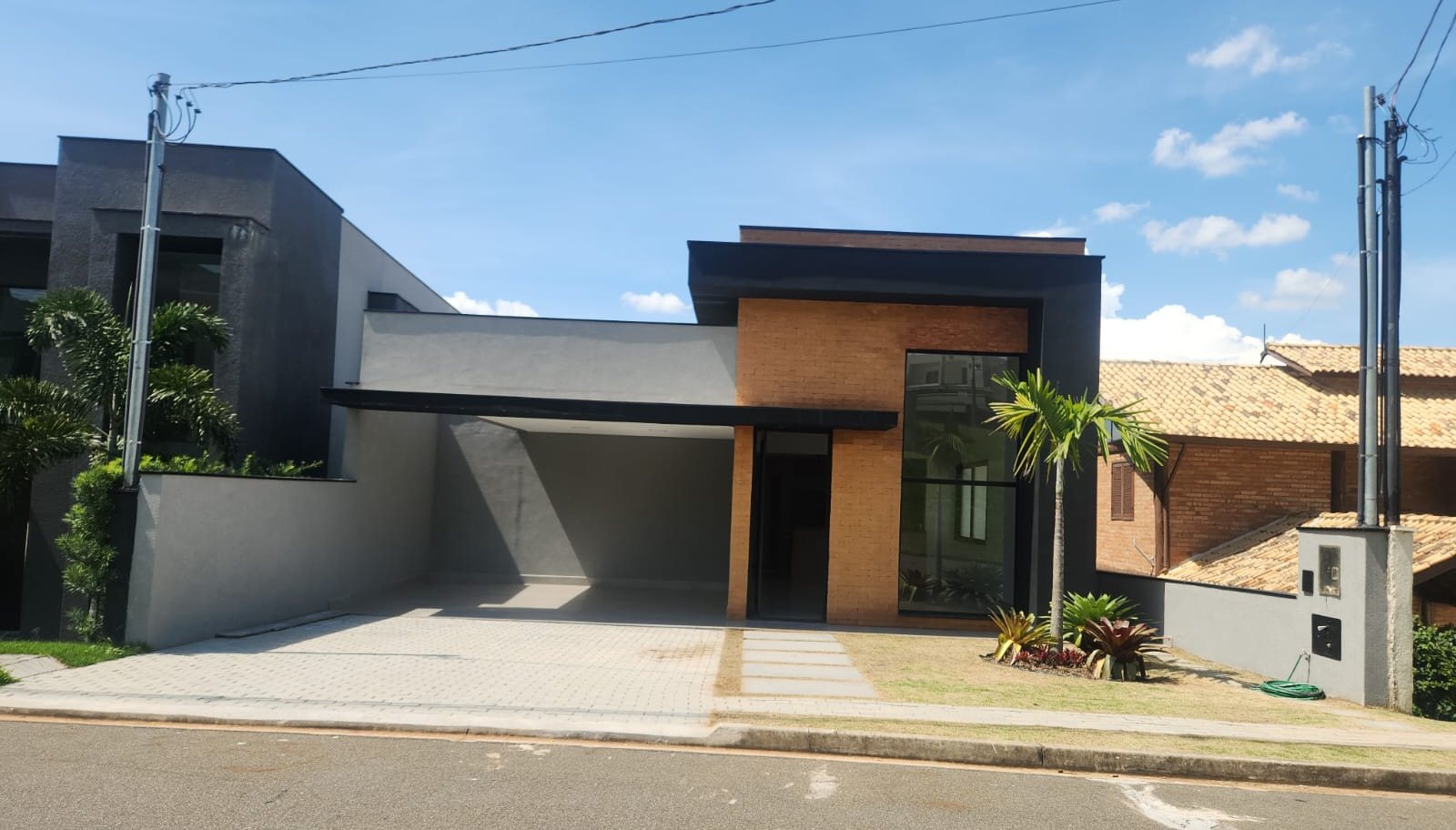 Fachada de casa térrea com volume revestido em plaqueta de tijolo aparente